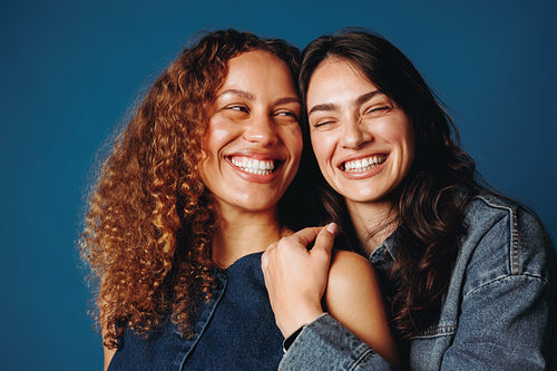 Joyful female friends laughing together in studio portrait