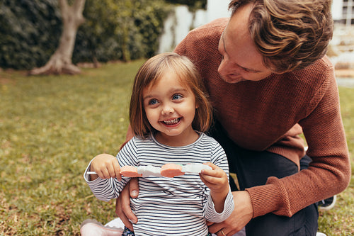 Little girl with her father outdoors holding a candy