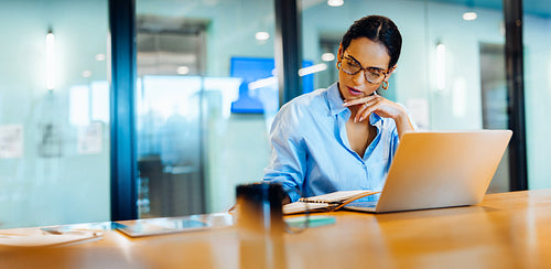 Focused business woman working on a laptop in a professional office setting