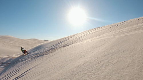 Motocross athlete creating dust while riding on sand dunes