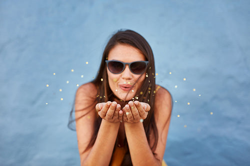 Young woman blowing sparkles