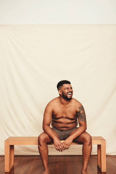 Shirtless young man laughing cheerfully in a studio