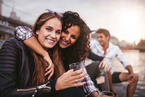 Happy female friends having fun with drinks on the lake