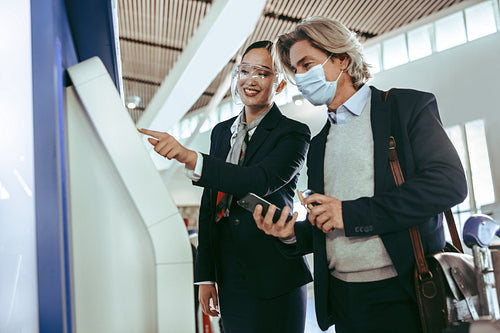 Airport staff assisting business traveler in self check in
