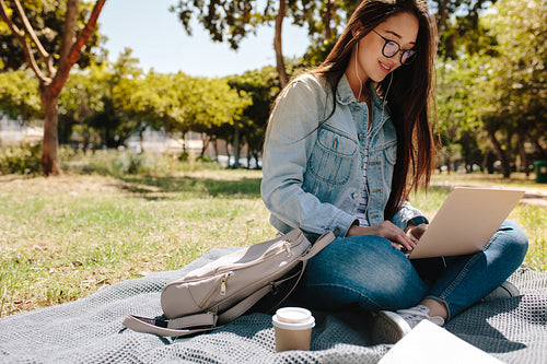 Student using laptop sitting in college campus