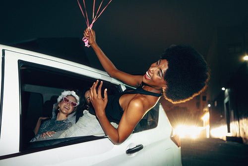 Group of friends celebrating a bachelorette during a nighttime car ride