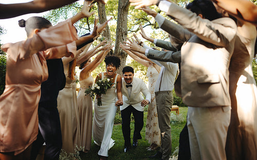 Newlywed couple celebrates joyfully amid cheering friends in outdoor ceremony