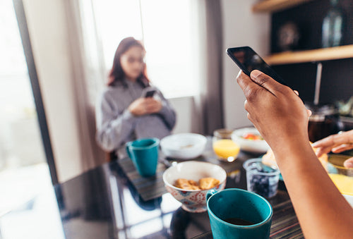 Couple eating breakfast whilst using mobile phones