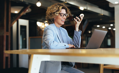 Woman talking on a phone call while working on a laptop in a coworking space