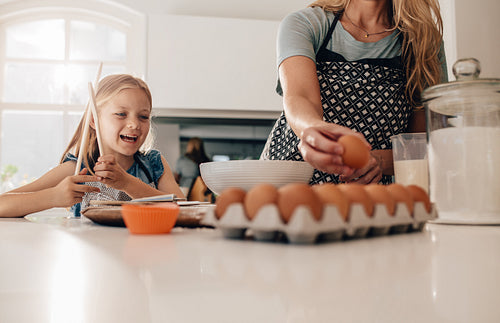 Little girl standing in kitchen with mother baking