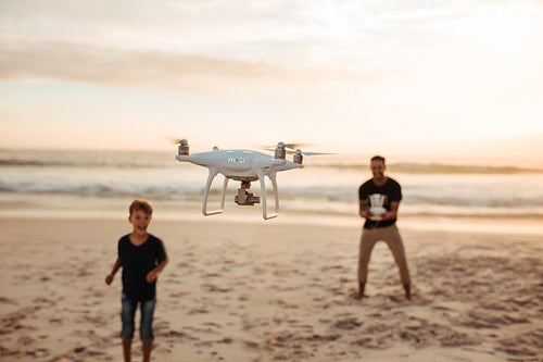 Father and son on summer vacation flying drone on beach