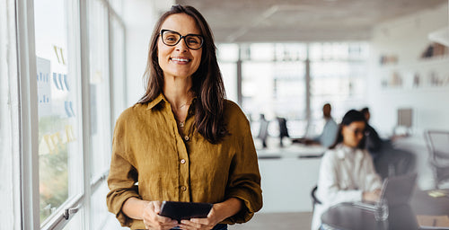 Happy business woman holding a tablet while standing in an office