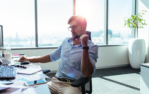 Businessman sitting at his work station in office.