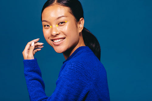 Portrait of a young woman smiling with four eyeliner dots on her face