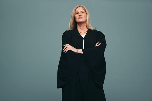 Female judge standing with her arms crossed in a studio