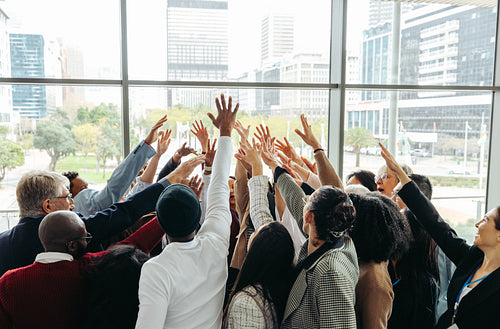 Celebrating teamwork: Diverse professionals huddling in a modern office