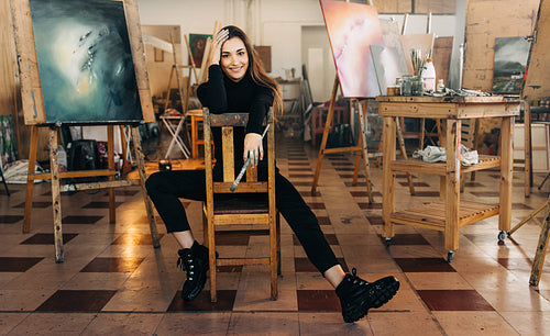 Cheerful female artist smiling at the camera in her workshop