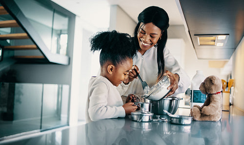 Woman teaching her daughter how to bake a cake at home