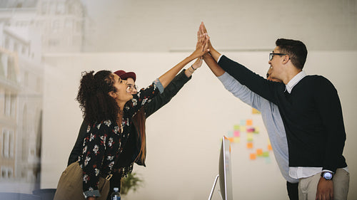 Business colleagues giving high five and celebrating in office