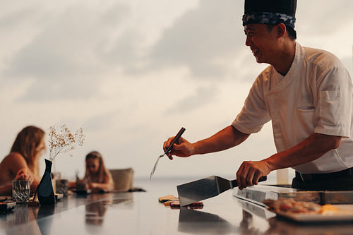 Chef preparing teppanyaki meal in front of diners at a fine restaurant
