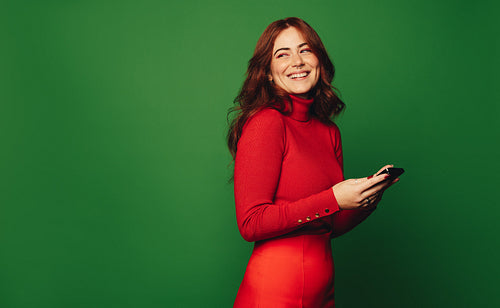 Stylish woman with colorful smartphone on green background - modern lifestyle communication