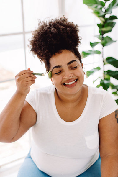 Woman massaging face skin with jade roller
