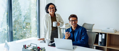 Two coworkers smile during casual office chat