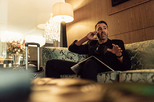 Mature businessman in hotel lobby talking on phone