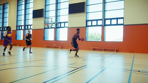 Young men playing basketball in gymnasium