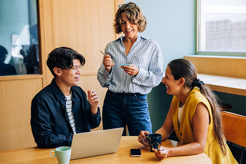 Three people having a lively discussion at a table in an office setting
