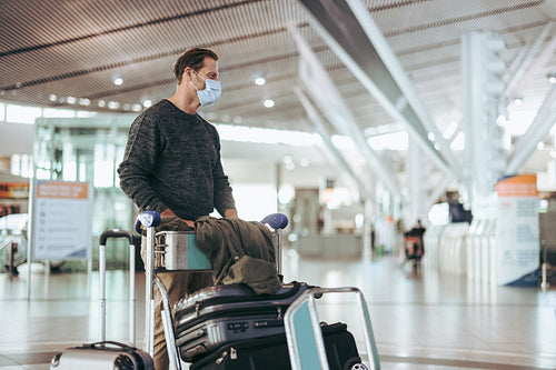 Man with luggage trolley waiting at airport