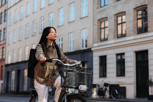 Young woman riding bicycle through quiet city street