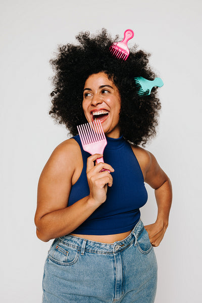 Woman with Afro hair having fun with fork combs in a studio