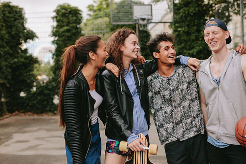 Happy teenage friends enjoying on basketball court