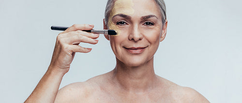 Senior woman applying liquid foundation