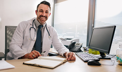 Confident doctor sitting at his clinic desk
