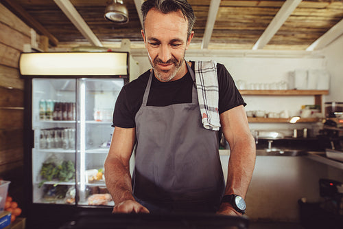 Barista using cashbox computer at cafe counter