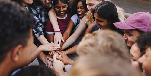 Multicultural teenagers putting their hands together in solidarity