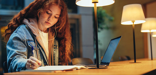 Student completing her college assignment in library