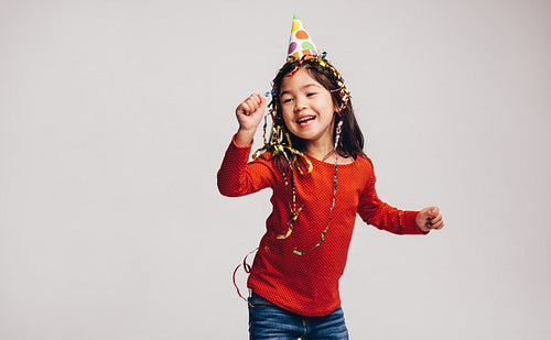 Little girl dancing wearing a party cap