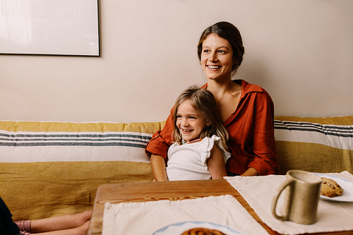 Mother and daughter smile on sofa at home
