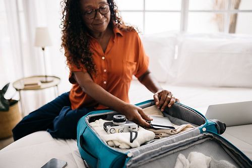 Senior woman packing her travel documents for a global adventure