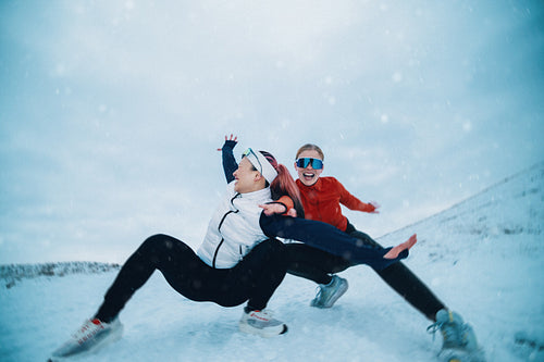 Women capturing playful winter poses after a snowy run