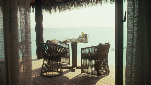 Woman steps out to enjoy a serene breakfast on an overwater bungalow deck