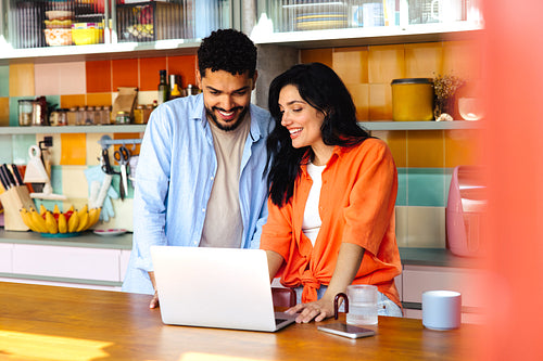 Couple using a laptop together in a modern kitchen setting