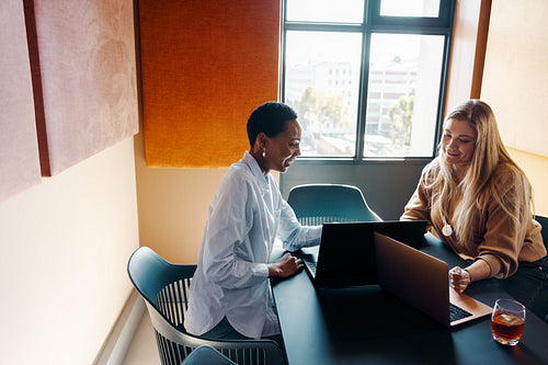 Colleagues working together in a modern office setting with laptops