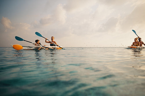 Adults and children kayaking in clear ocean waters under a sunny sky