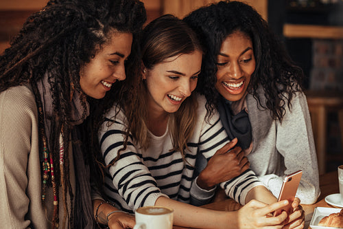 Friends at a cafe looking at mobile phone