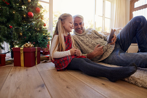 Grandfather and granddaughter using digital tablet at home during Christmas