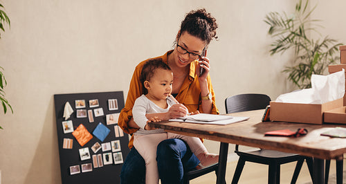 Mother talking on smart phone at home office